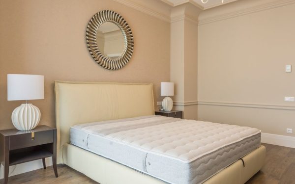 Spacious bedroom featuring modern decor, elegant lighting, and a plush bed with neutral tones.