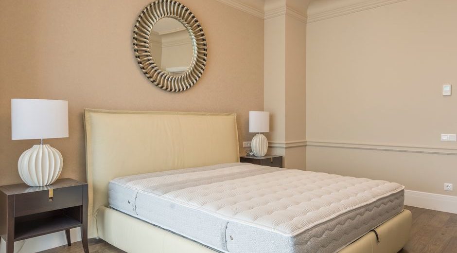 Spacious bedroom featuring modern decor, elegant lighting, and a plush bed with neutral tones.