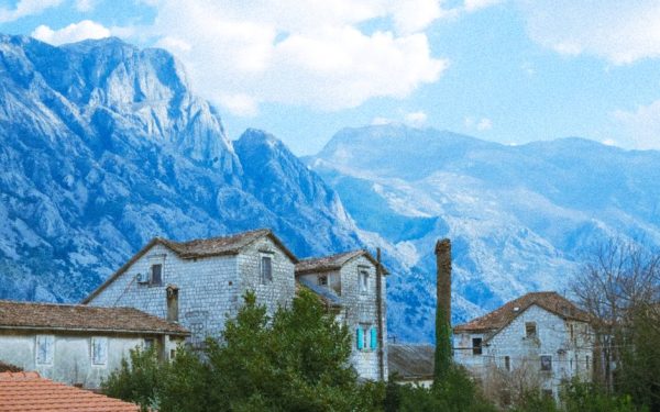 Charming village houses set against a stunning mountain landscape under a bright sky.
