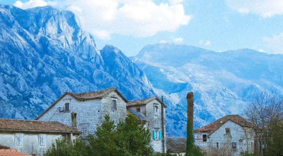 Charming village houses set against a stunning mountain landscape under a bright sky.
