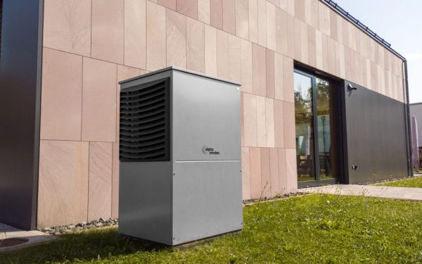 A modern heat pump unit installed outdoors next to a contemporary building, showcasing renewable energy technology.