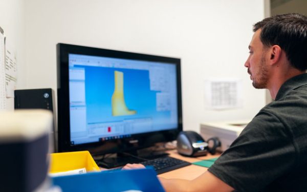 Engineer working on prosthetic design using specialized software in an office setting.