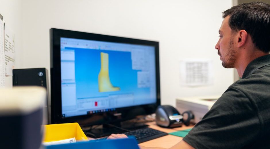 Engineer working on prosthetic design using specialized software in an office setting.