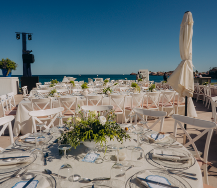 Outdoor beachfront wedding setup with elegant table arrangements and floral decor.