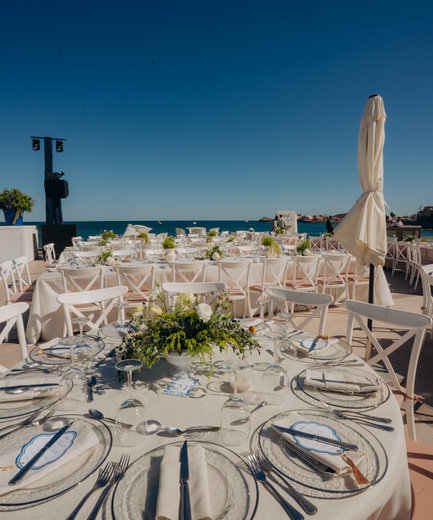 Outdoor beachfront wedding setup with elegant table arrangements and floral decor.